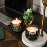 Two lit Candledust refillable powdered candles in elegant dark glass containers for eco-friendly home aromatherapy